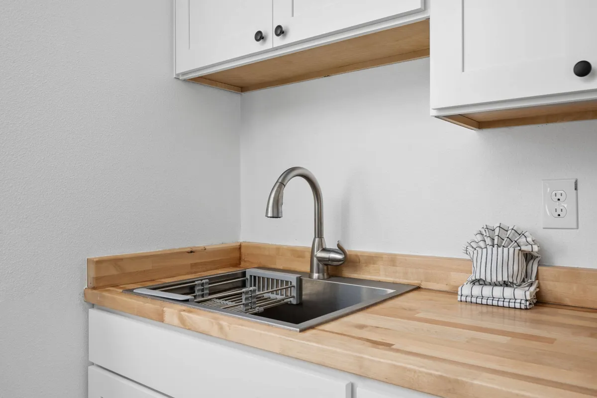 A close-up of the kitchen sink area, with neatly arranged kitchenware and a functional countertop. The space is inviting and practical, supporting meal preparation, cleanup, and casual conversation in a relaxed setting.